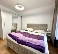 Hálószoba egy kétszobás lakásban fa dekor padlóval, szekrénnyel és ággyal.