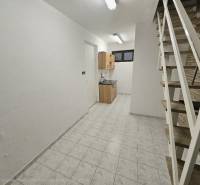 Belső tér fehér falakkal, konyhaszekrénnyel, lépcsővel és fa dekorációjú padlóval.