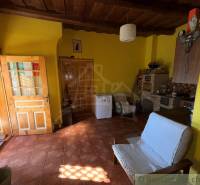 Szoba egy családi házban téglapadlóval, fa mennyezettel és sárga falakkal.