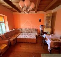 Nappali sarokkanapéval, fa hatású padlóval és cserépkályhával egy családi házban.