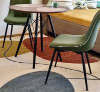 1 szobás lakás belső tere színes szőnyeggel, asztallal és zöld székekkel, dekoratív padlóval.