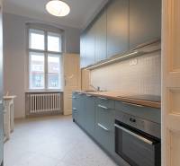 Konyha fehér csempével egy háromszobás lakásban, modern konyhabútorral és tűzhellyel felszerelve.