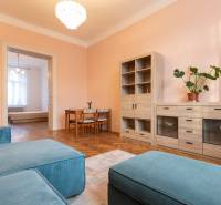 Nappali egy háromszobás lakásban, fa dekorációjú padlóval és pasztell színű falakkal.