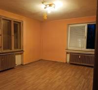 Szoba egy kétszobás lakásban, narancssárga falak, fa dekoros padló, radiátorok.