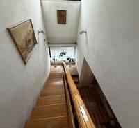 Családi ház lépcsője, falon egy képpel és egy növénnyel az ablak mellett.