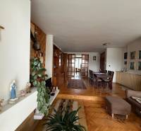 Nappali egy családi házban, fa dekoros padlóval, étkezőasztallal és kereszttel a falon.