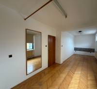 Egy családi ház szobája fa dekorációjú padlóval, tükörrel és ablakkal.