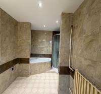 Fürdőszoba családi házban márvány megjelenésű csempével és sarokkáddal.