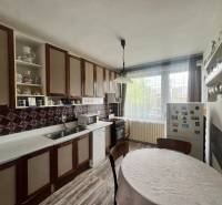 Konyha családi házban fa szekrényekkel, kerek asztallal és fa dekorációjú padlóval.