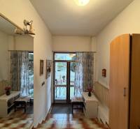 Családi ház belső tere tükörrel, szekrénnyel, padlóburkolattal és kilátással a kertre.