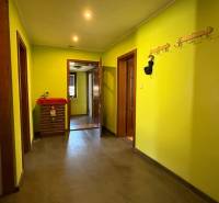 Folyosó fogasokkal és sárga falakkal, fa dekorációjú padlóval egy családi házban.