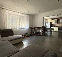 Nappali egy családi házban, kilátással a konyhára, fa mintázatú padlóval.