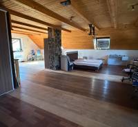 Tetőtéri szoba ággyal, szekrénnyel és fa dekorációjú padlóval egy családi házban.