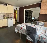 Konyha családi házban kerámia burkolattal, étkezőasztallal és mosogatógéppel.