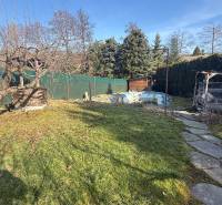 Családi ház kertje Lutilában fákkal és sétánnyal napos környezetben.