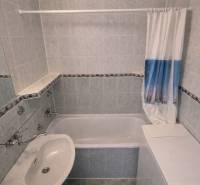 Fürdőszoba káddal és mosdóval egy kétszobás lakásban, csempézett falakkal.