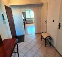 Folyosó íves átjáróval egy kétszobás lakásban, fa dekorációjú padló, tükör, pad.