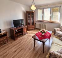 Nappali egy kétszobás lakásban, fa dekor padlóval és klasszikus bútorokkal.