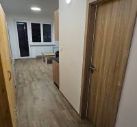 Garzonlakás fa dekor padlóval, fehér falakkal és bútorokkal.