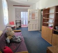 Nappali egy családi házban kanapéval, polcos szekrénnyel és játékkal a padlón.