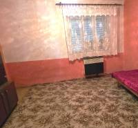 Szoba családi házban szőnyeggel, ággyal és szekrénnyel, függönnyel az ablakon.