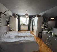 Hálószoba egy háromszobás lakásban szekrénnyel, ággyal és fa dekorációjú padlóval.