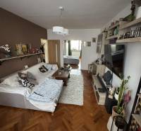 Nappali kanapéval, asztallal és fa dekorációjú padlóval egy háromszobás lakásban.