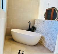 Fürdőszoba családi házban szabadon álló káddal és kőburkolatú fallal.