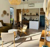 Családi ház belső tere fonott kiegészítőkkel és konyhával, fa dekorációjú padlóval.