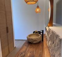 Családi ház belső tere kő mosdóval, fa munkalappal és függőlámpákkal.