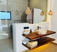 Fürdőszoba egy családi házban, mosdókagylóval egy fa polcon és fa dekorációjú padlóval.