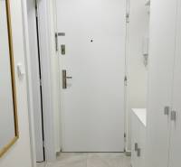 Bejárati ajtó a garzonlakásban fehér falakkal és csempével, tükör a falon.