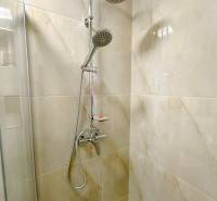 Zuhanykabin kerámia burkolattal és esőztető zuhannyal a garzonlakásban.