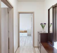 Folyosó egy 2 szobás lakásban fa dekor padlóval és sötét bútorokkal.