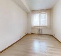 Világos szoba ablakkal és fa dekorációjú padlóval egy kétszobás lakásban.