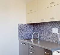 Konyha mozaik csempével egy kétszobás lakásban, fa dekorációjú konyhaszekrényekkel.