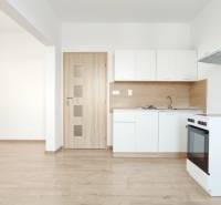 Konyha egy kétszobás lakásban fehér szekrényekkel, tűzhellyel és fa dekorációjú padlóval.