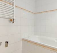 Fürdőszoba káddal és fehér csempével egy kétszobás lakásban.