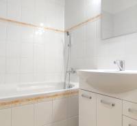 Fürdőszoba egy kétszobás lakásban fehér csempével és káddal.