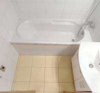 Fürdőszoba egy kétszobás lakásban káddal, mosdóval és fehér csempével.