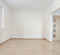 Nappali egy kétszobás lakásban fa dekor padlóval és konyhasarokkal.