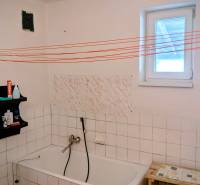 Fürdőszoba családi házban káddal, polccal és fehér csempékkel.