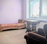 Szoba családi házban kinyitható kanapéval és fotellel, fa dekoros padlóval.