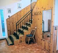 Családi ház belső tere fa burkolattal, tükörrel, lépcsővel és fa dekoros padlóval.