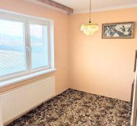 Egy családi házban van egy szoba szőnyegpadlóval, függőlámpával és festménnyel.