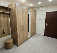 Folyosó egy kétszobás lakásban fa dekorációjú bútorokkal és beépített tükörrel.