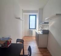 Keskeny iroda fekete asztallal, székekkel és fa dekorációjú padlóval.