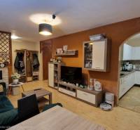 Nappali egy háromszobás lakásban fa dekorációjú padlóval és nyitott konyhával.