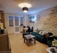 Nappali egy háromszobás lakásban fa dekor padlóval és dekoratív elemekkel.