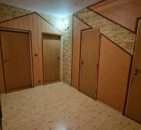 Folyosó három ajtóval és fa dekorációjú padlóval egy háromszobás lakásban.